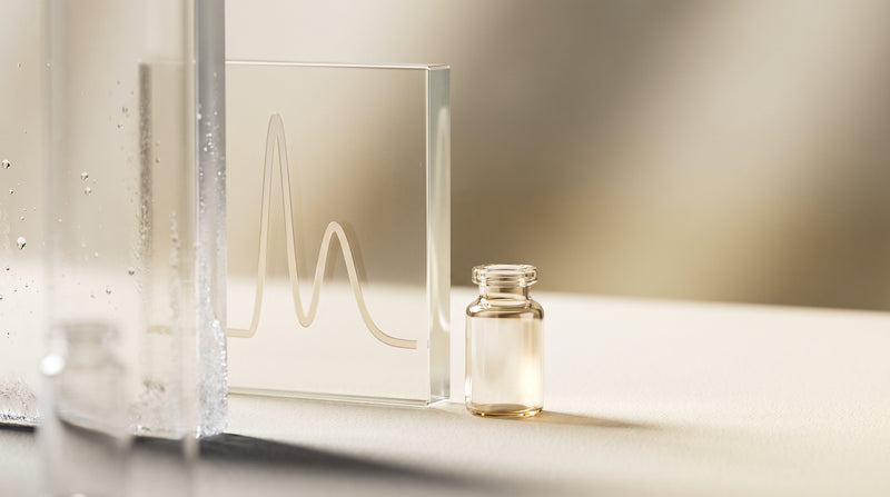 Abstract still-life of a laboratory glass vial and an etched chromatography curve on frosted glass, in warm gold and ivory tones
