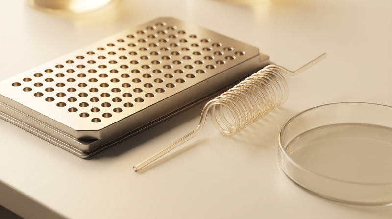 Abstract laboratory still-life of a mass spectrometer sample plate and coiled capillary tube in warm gold and ivory tones
