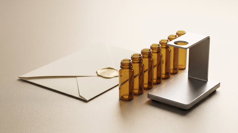 Abstract still-life of amber glass laboratory vials beside a certificate-style document, warm gold and ivory tones, soft studio light