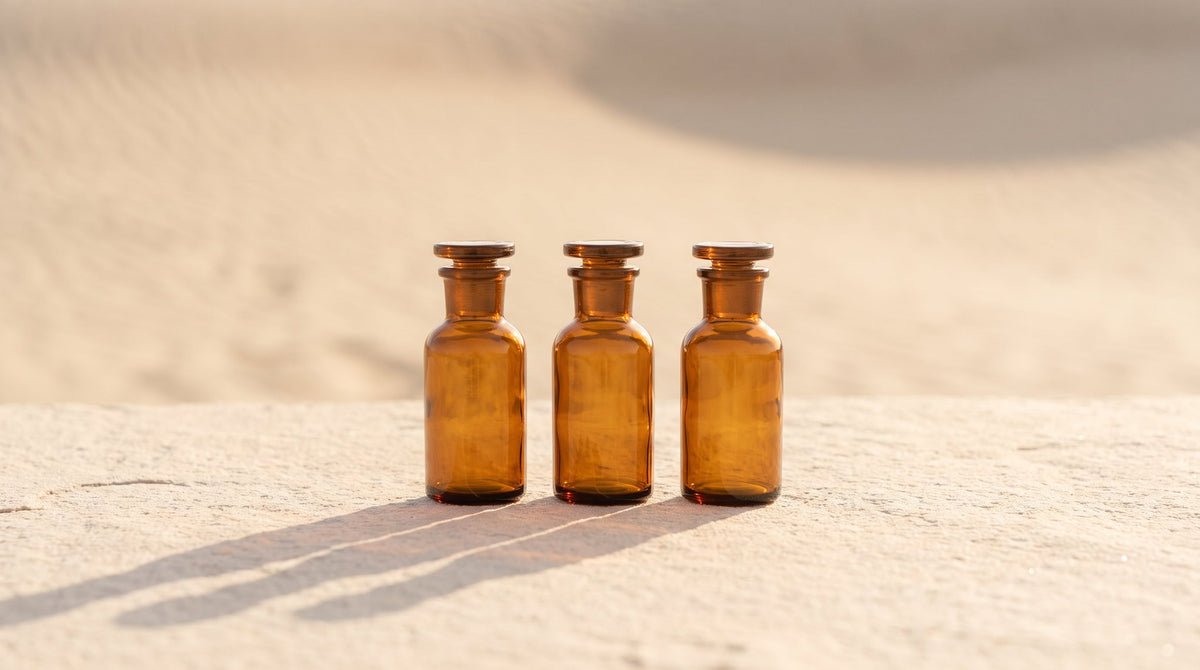 A minimalist row of amber research vials on a cream surface in warm golden light