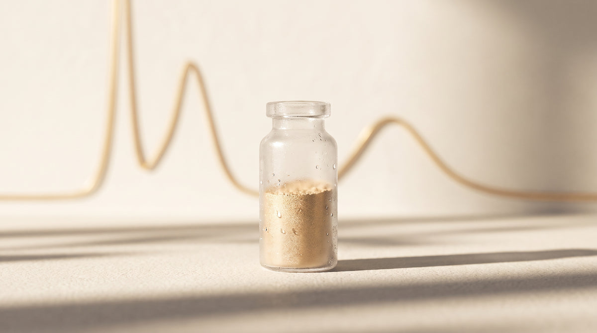 Abstract still-life of a frosted glass laboratory vial with fine powder, warm gold and champagne studio lighting, minimalist composition